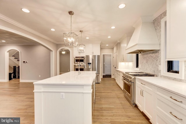 kitchen featuring premium appliances, arched walkways, premium range hood, and a kitchen island