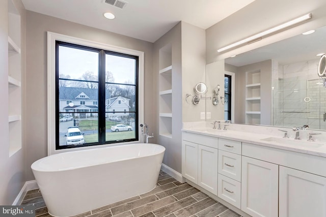 bathroom featuring a soaking tub, visible vents, wood tiled floor, a sink, and baseboards