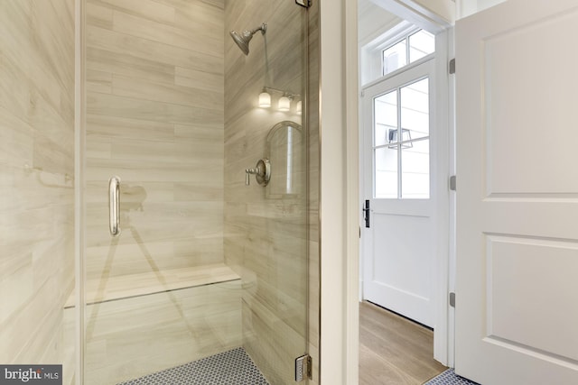 bathroom with a healthy amount of sunlight, a shower stall, and wood finished floors