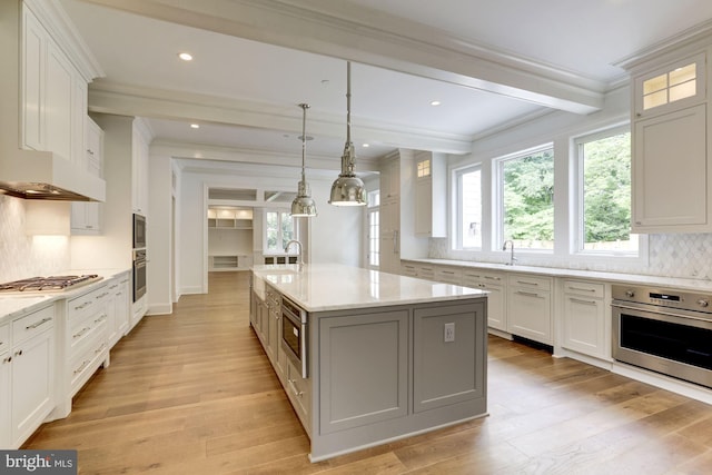 kitchen with appliances with stainless steel finishes, a kitchen island with sink, and white cabinets