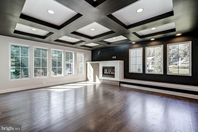 unfurnished living room featuring baseboards, dark wood-type flooring, a wealth of natural light, and a glass covered fireplace