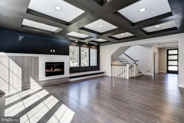 unfurnished living room with stairway, a glass covered fireplace, wood finished floors, coffered ceiling, and baseboards