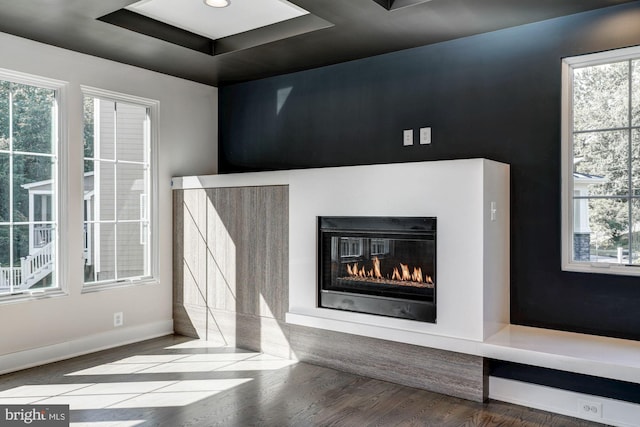 room details with a tray ceiling, baseboards, wood finished floors, and a glass covered fireplace