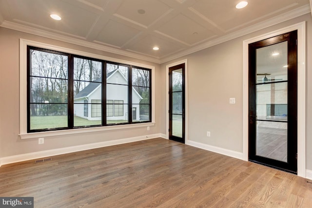 unfurnished room featuring baseboards, visible vents, coffered ceiling, ornamental molding, and wood finished floors