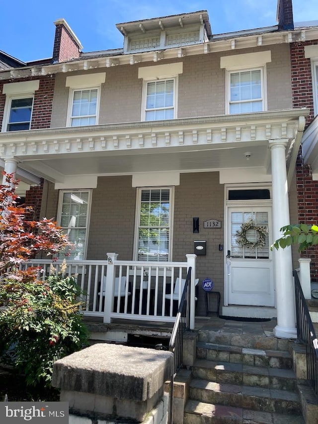 view of front of home with covered porch and brick siding