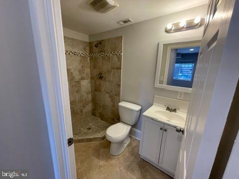 bathroom featuring tiled shower, vanity, and toilet