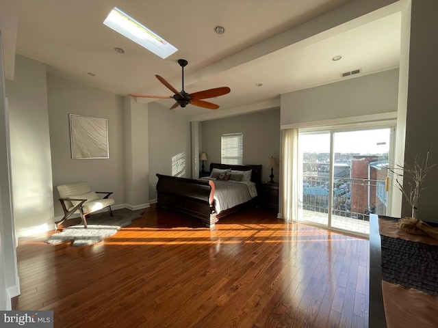 bedroom with a skylight, access to outside, dark hardwood / wood-style floors, and ceiling fan