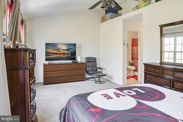 bedroom with ceiling fan, ensuite bathroom, and light colored carpet