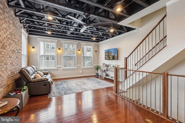 interior space with hardwood / wood-style flooring, ceiling fan, and brick wall