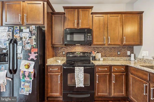 kitchen featuring light stone countertops, decorative backsplash, and black appliances