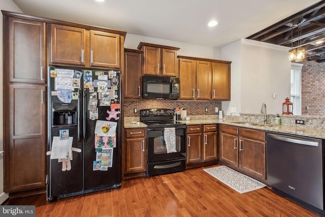 kitchen with tasteful backsplash, dark hardwood / wood-style floors, sink, and black appliances