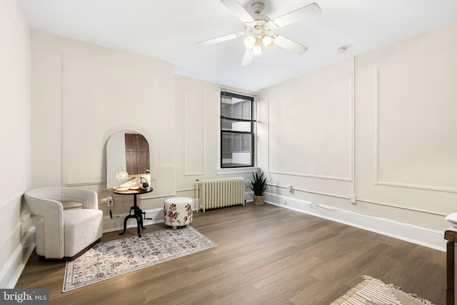 sitting room featuring ceiling fan, radiator heating unit, and wood-type flooring