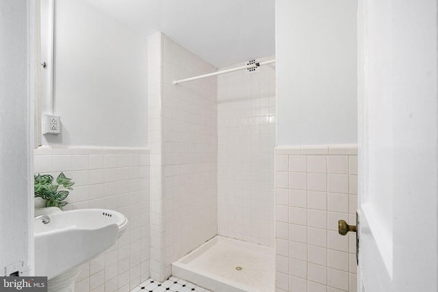 bathroom featuring a tile shower, sink, tile patterned flooring, and tile walls