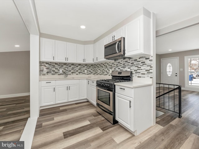 kitchen featuring white cabinets, sink, stainless steel appliances, and light hardwood / wood-style floors