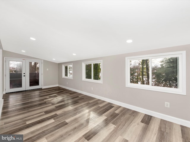 empty room featuring lofted ceiling, french doors, and hardwood / wood-style flooring