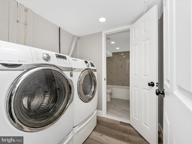 laundry room with hardwood / wood-style flooring and washing machine and dryer