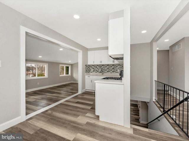 kitchen featuring white cabinetry, decorative backsplash, range, light hardwood / wood-style flooring, and sink