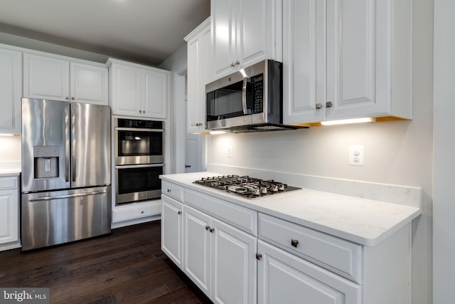 kitchen featuring appliances with stainless steel finishes, dark hardwood / wood-style flooring, white cabinetry, and light stone counters