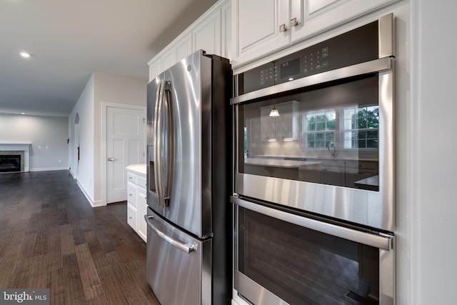 kitchen featuring dark wood-type flooring, appliances with stainless steel finishes, and white cabinetry