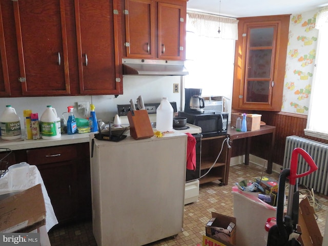 kitchen with electric range, wood walls, radiator, and washer / clothes dryer