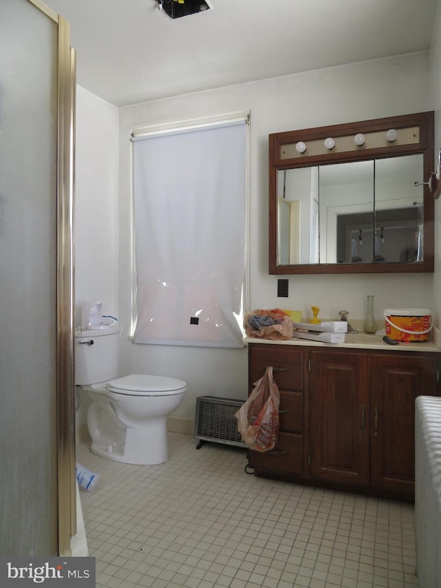 bathroom with tile patterned floors, toilet, vanity, and radiator