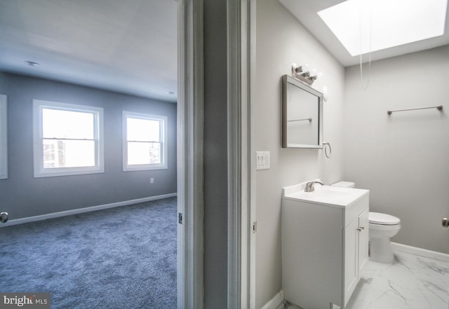 bathroom featuring toilet, vanity, and a skylight