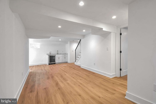 unfurnished living room featuring indoor bar, beverage cooler, and light hardwood / wood-style flooring