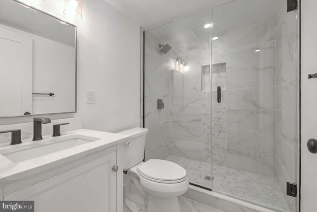 bathroom featuring vanity, a shower with shower door, and toilet