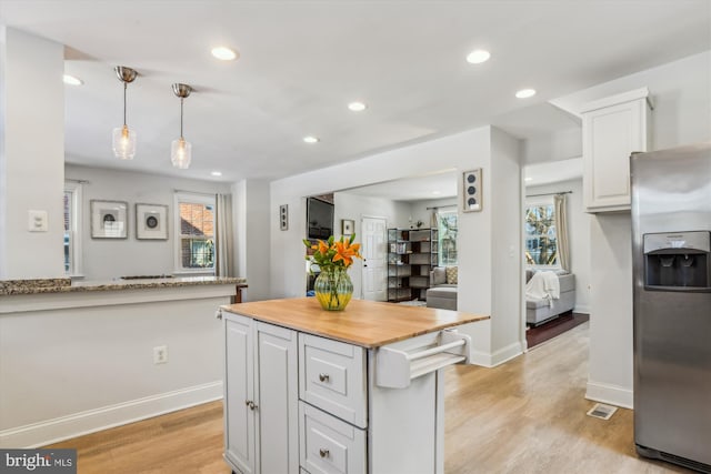 kitchen with white cabinetry, wooden counters, stainless steel fridge, pendant lighting, and light hardwood / wood-style floors