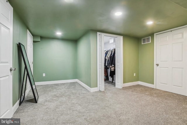 unfurnished bedroom featuring a walk in closet and light carpet