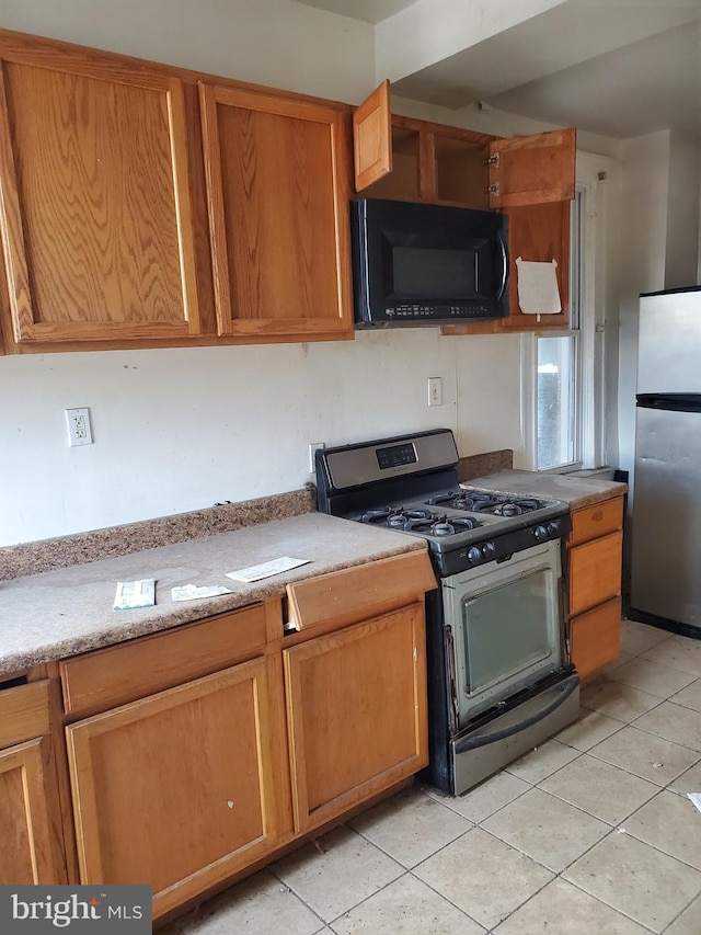 kitchen featuring light stone countertops, light tile patterned floors, and appliances with stainless steel finishes