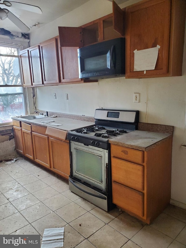 kitchen with gas range, sink, ceiling fan, and light tile patterned flooring