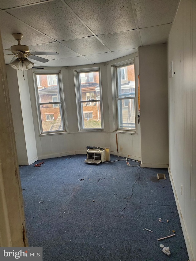 unfurnished room featuring a paneled ceiling, a healthy amount of sunlight, carpet floors, and ceiling fan