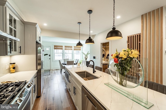 kitchen featuring sink, hanging light fixtures, light stone countertops, appliances with stainless steel finishes, and gray cabinetry