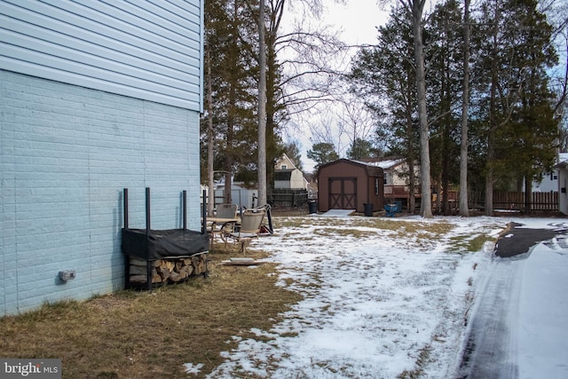 yard covered in snow featuring a shed