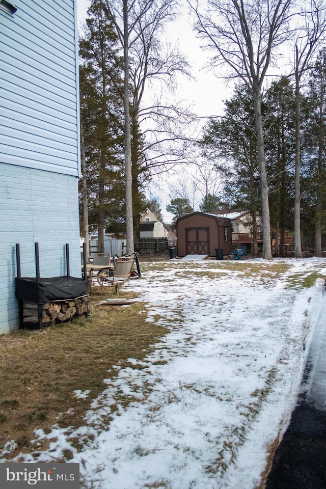 yard covered in snow featuring an outbuilding and a garage