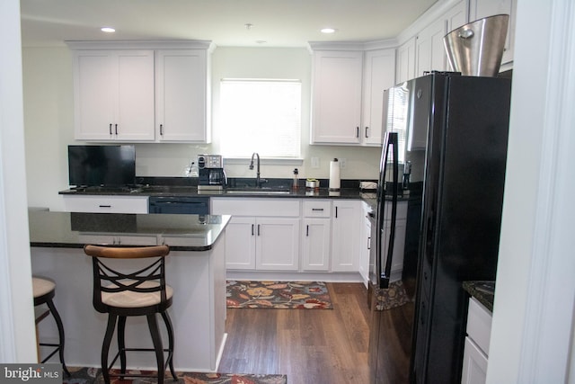 kitchen with sink, a breakfast bar area, white cabinets, and black appliances