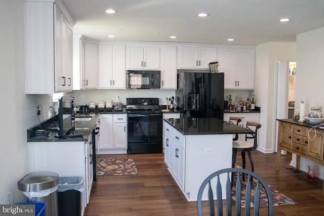 kitchen with white cabinetry, dark hardwood / wood-style floors, black appliances, and a center island