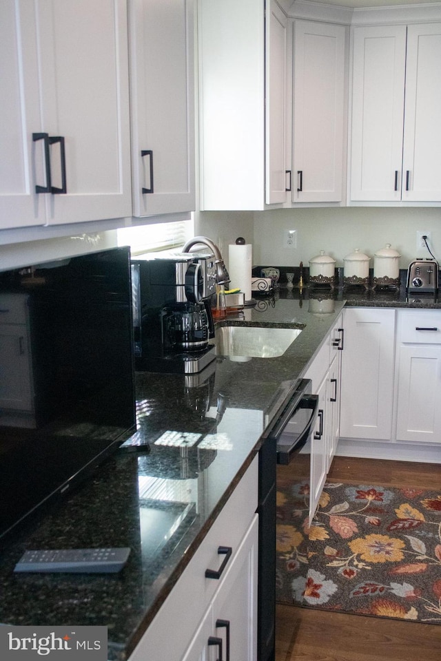 kitchen featuring white cabinetry, dishwasher, and dark stone countertops