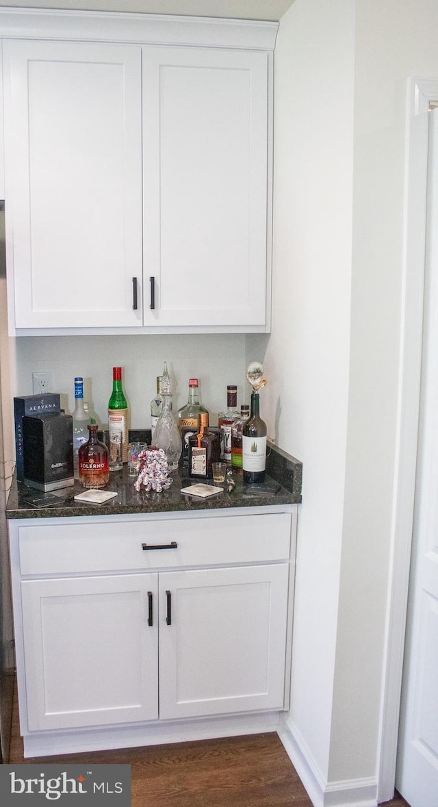 bar featuring white cabinetry, dark stone countertops, and dark hardwood / wood-style flooring