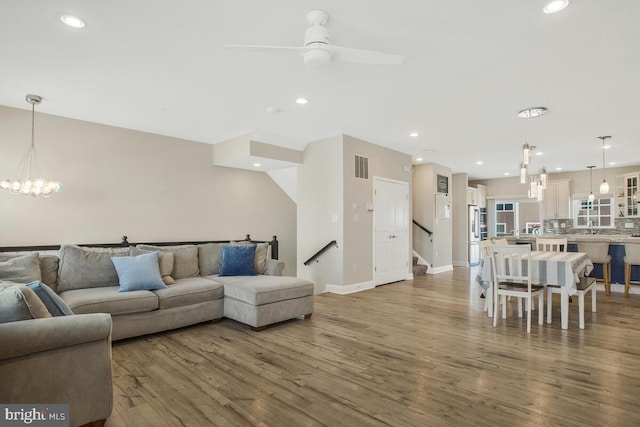 living room with hardwood / wood-style flooring and ceiling fan with notable chandelier