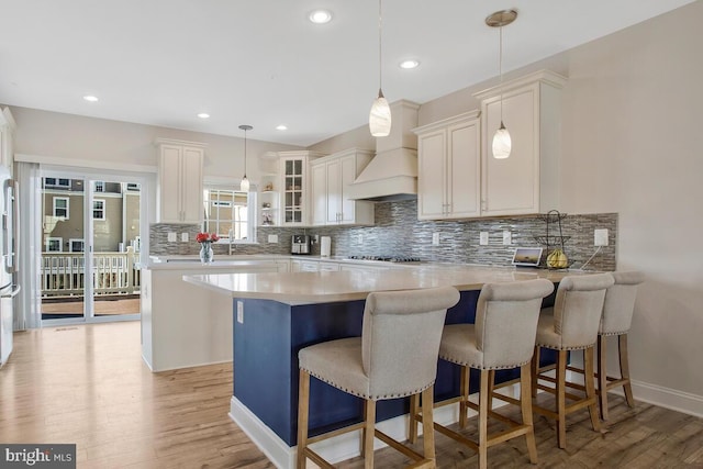 kitchen with appliances with stainless steel finishes, white cabinetry, a kitchen bar, hanging light fixtures, and a center island