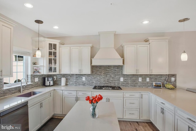 kitchen with pendant lighting, black dishwasher, sink, custom exhaust hood, and stainless steel gas cooktop