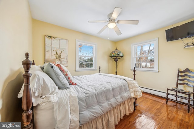 bedroom with ceiling fan, baseboard heating, and wood-type flooring