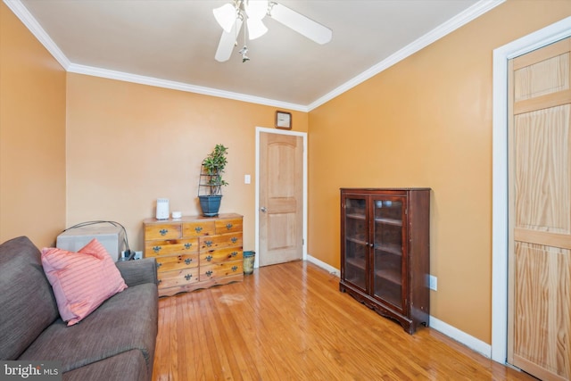 living area with ceiling fan, wood-type flooring, and ornamental molding