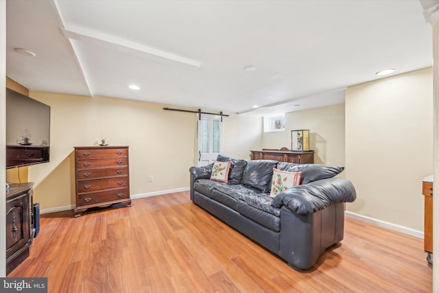 living room with a barn door and light wood-type flooring