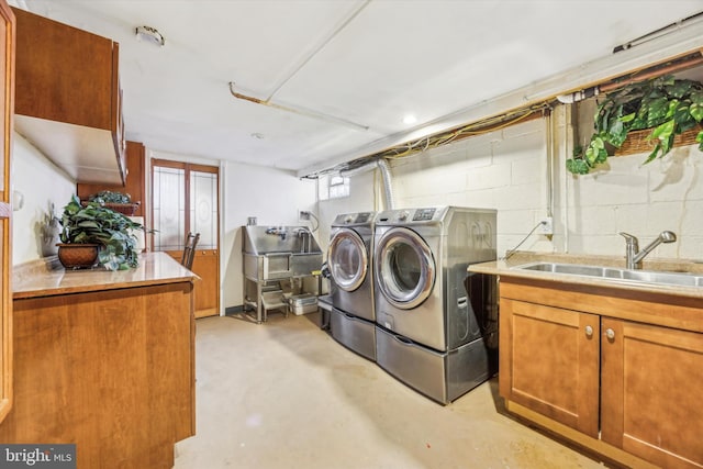 washroom with sink, independent washer and dryer, and cabinets