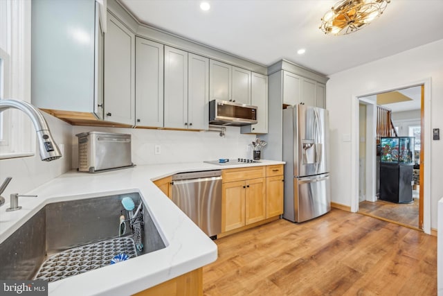 kitchen featuring sink, backsplash, light hardwood / wood-style floors, and stainless steel appliances