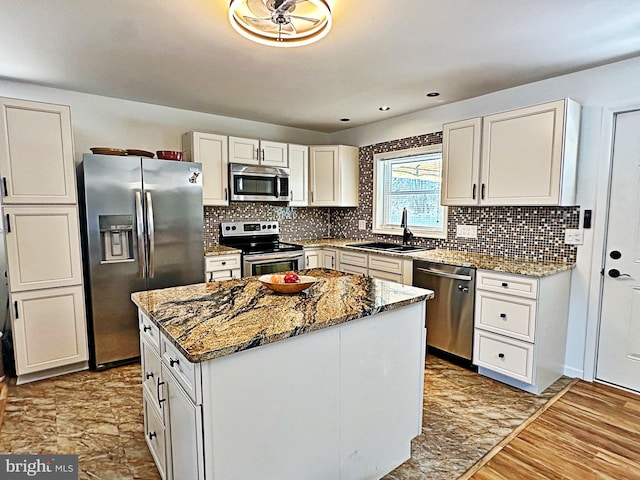 kitchen featuring stainless steel appliances, backsplash, a sink, and light stone countertops