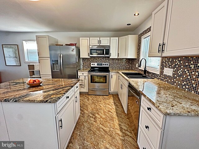 kitchen with appliances with stainless steel finishes, a sink, light stone counters, and decorative backsplash